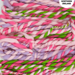 Colorful handspun yarn with pink, green, and purple hues on a white background.
