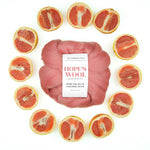 A ball of pink Corriedale wool surrounded by sliced pink grapefruits