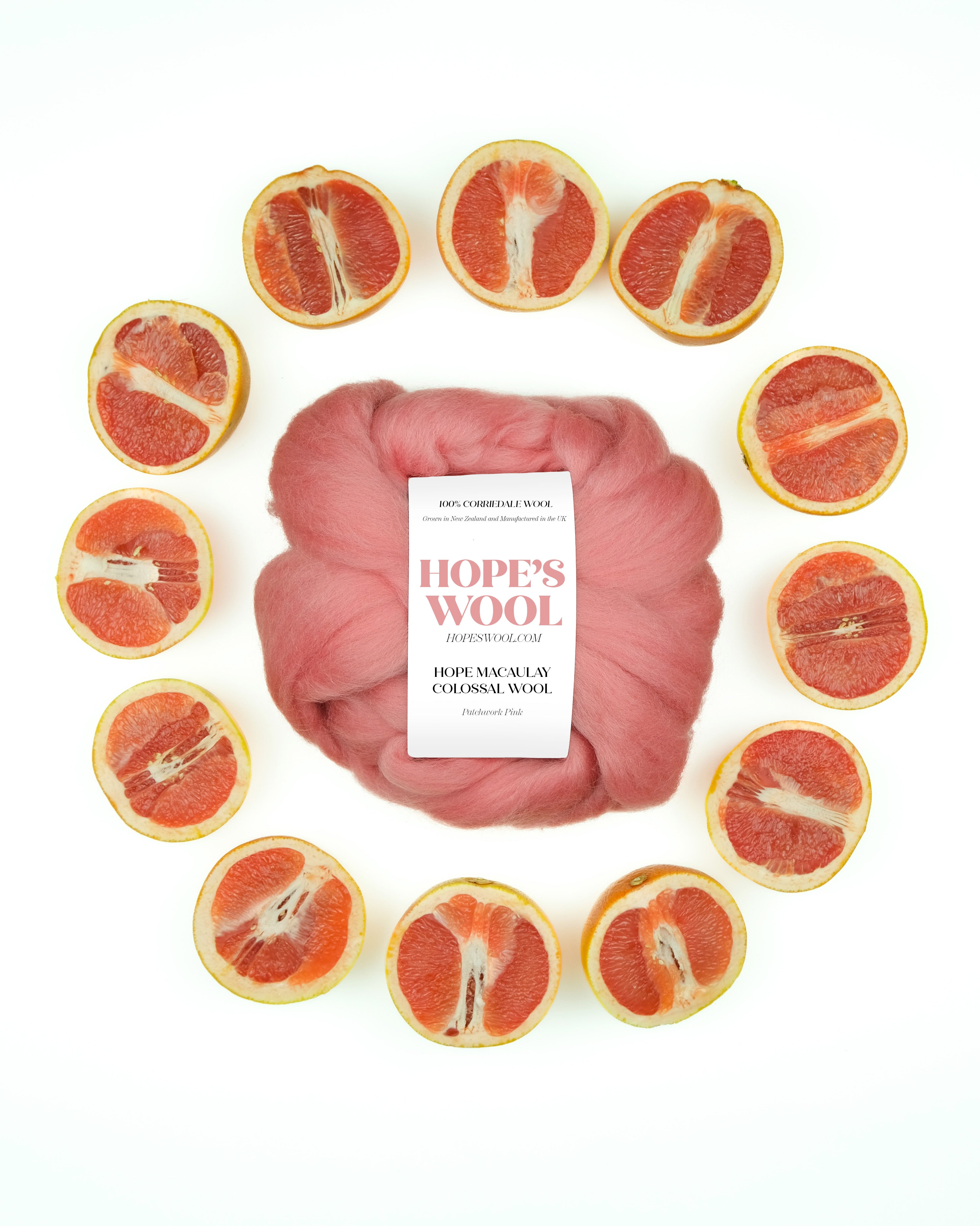 A ball of pink Corriedale wool surrounded by sliced pink grapefruits