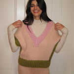 A woman in a pink, cream and green vest standing with a white door