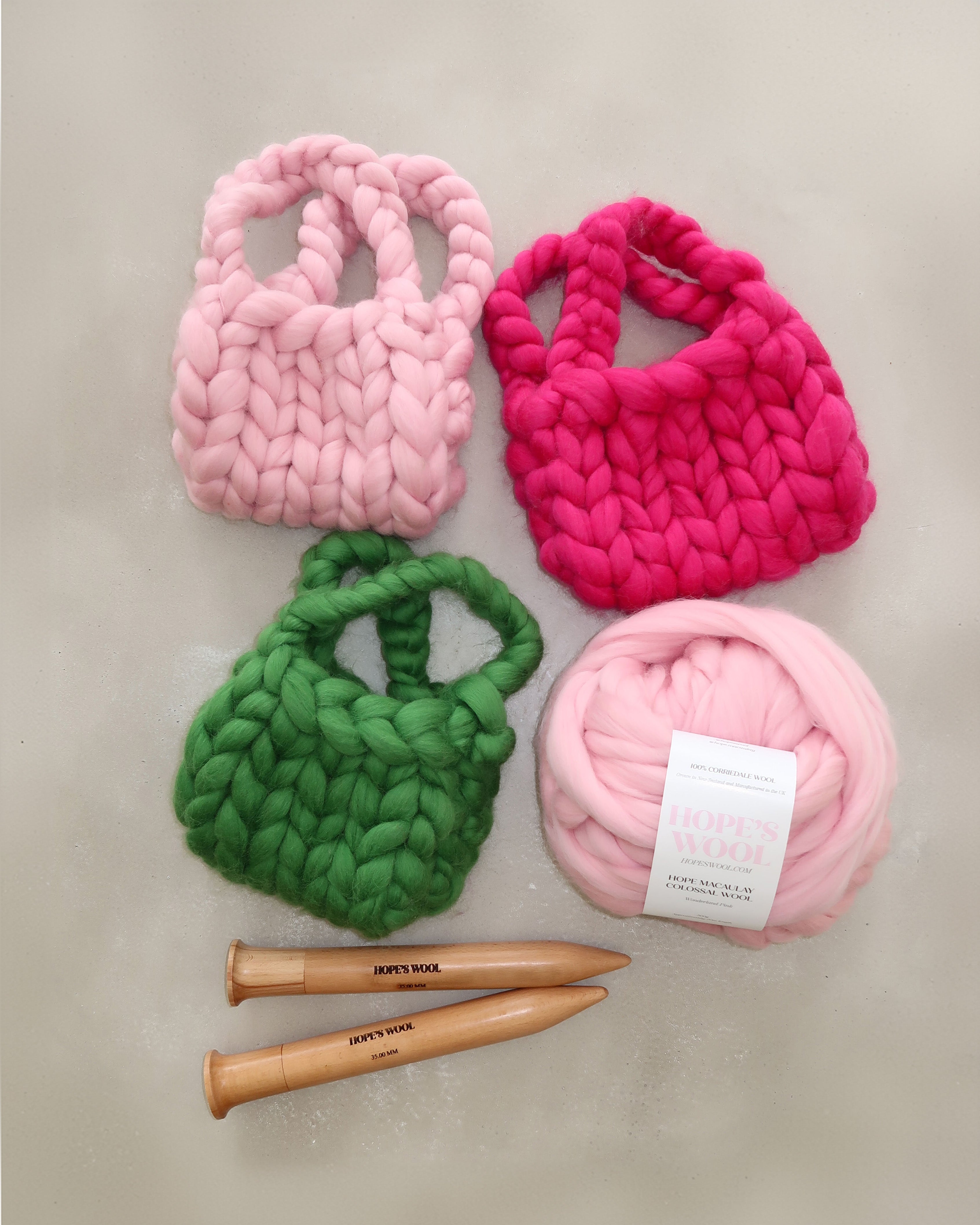 Hands holding up balls of Corriedale wool in Pink, Blue and Green 