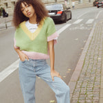 A woman in jeans and a vest posing on a street in a casual and stylish manner.