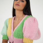 A woman wearing a colourful knitted top in front of a white background