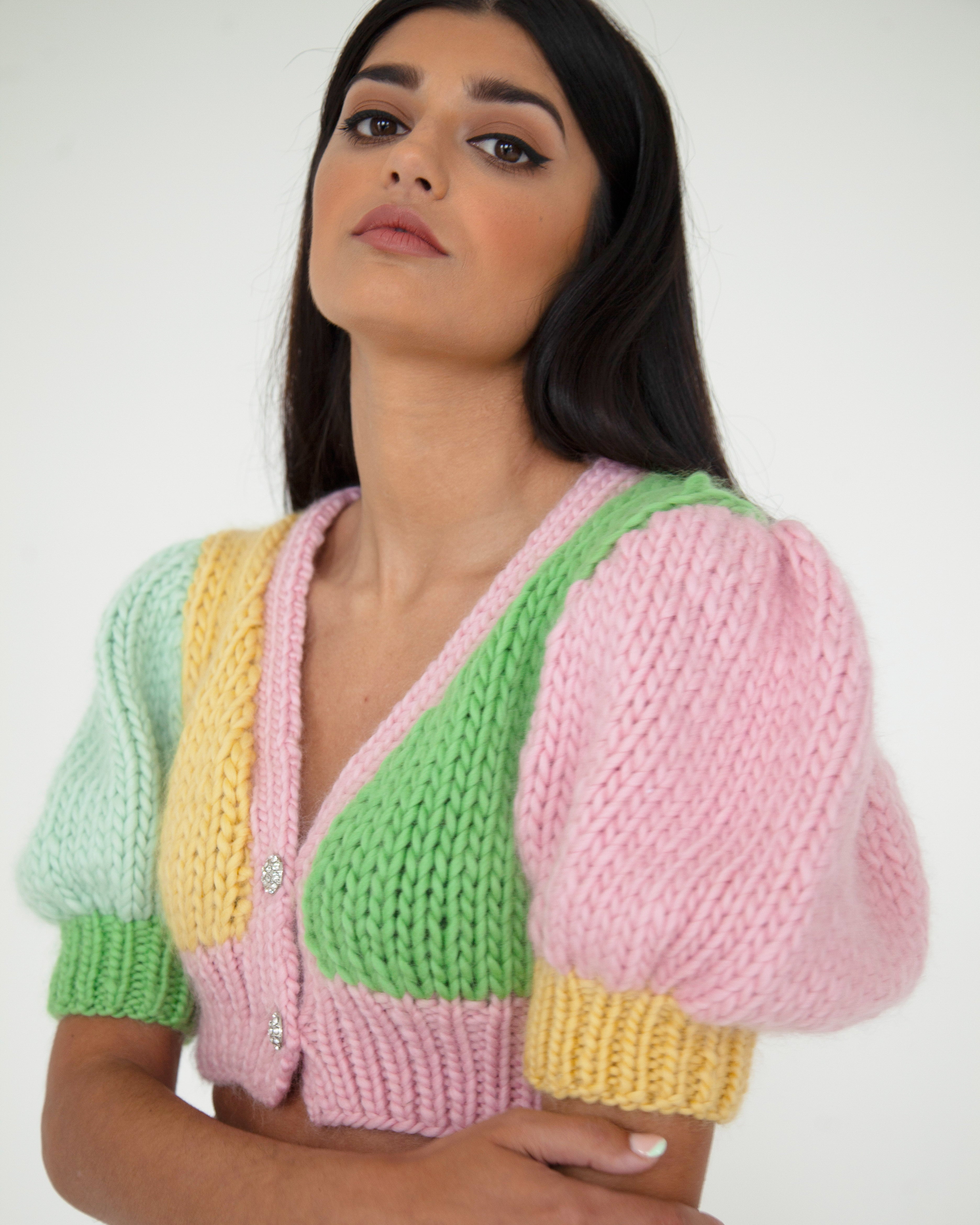 A woman wearing a colourful knitted top in front of a white background