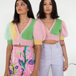 Two woman standing side by side wearing colourful knitted tops