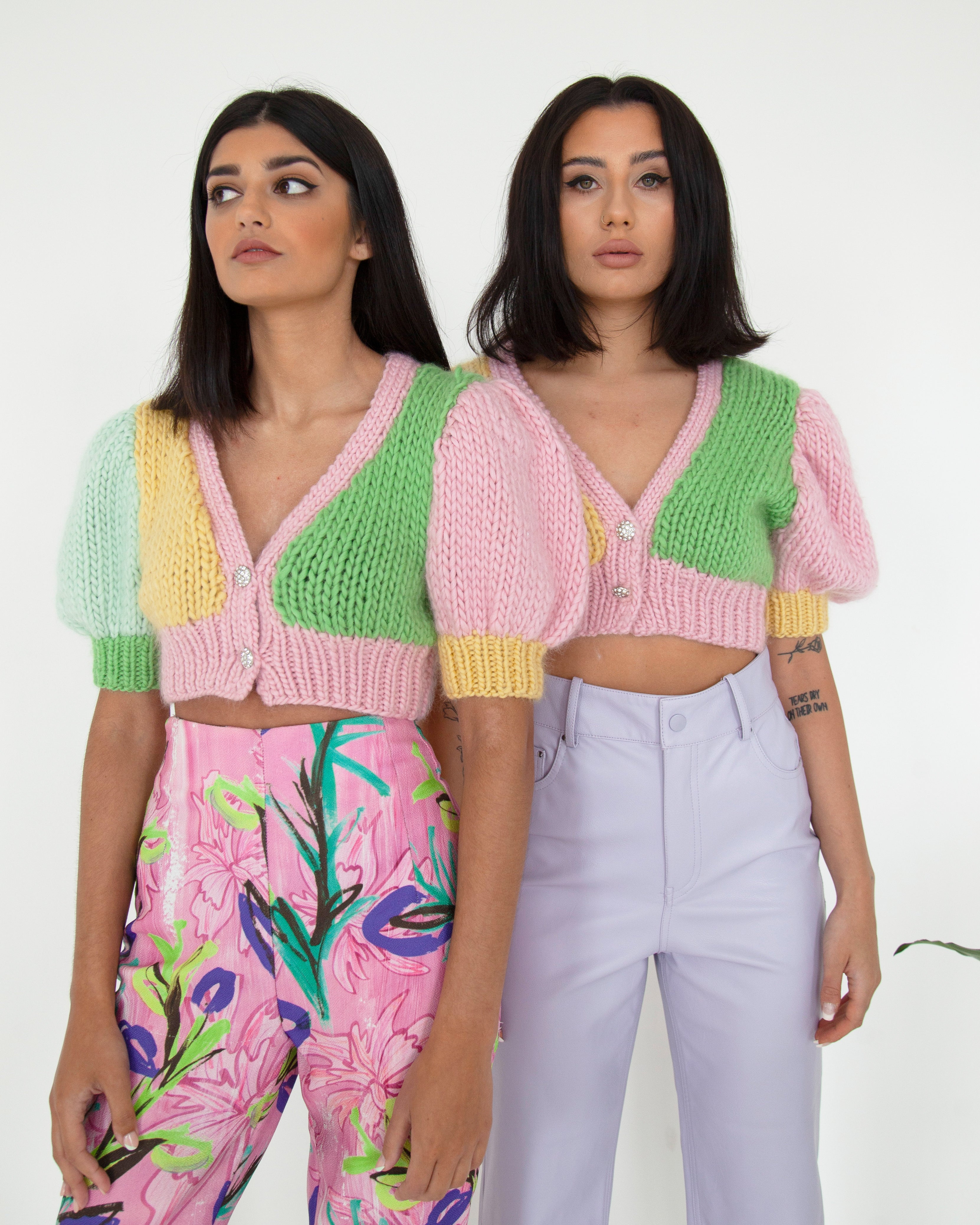 Two woman standing side by side wearing colourful knitted tops