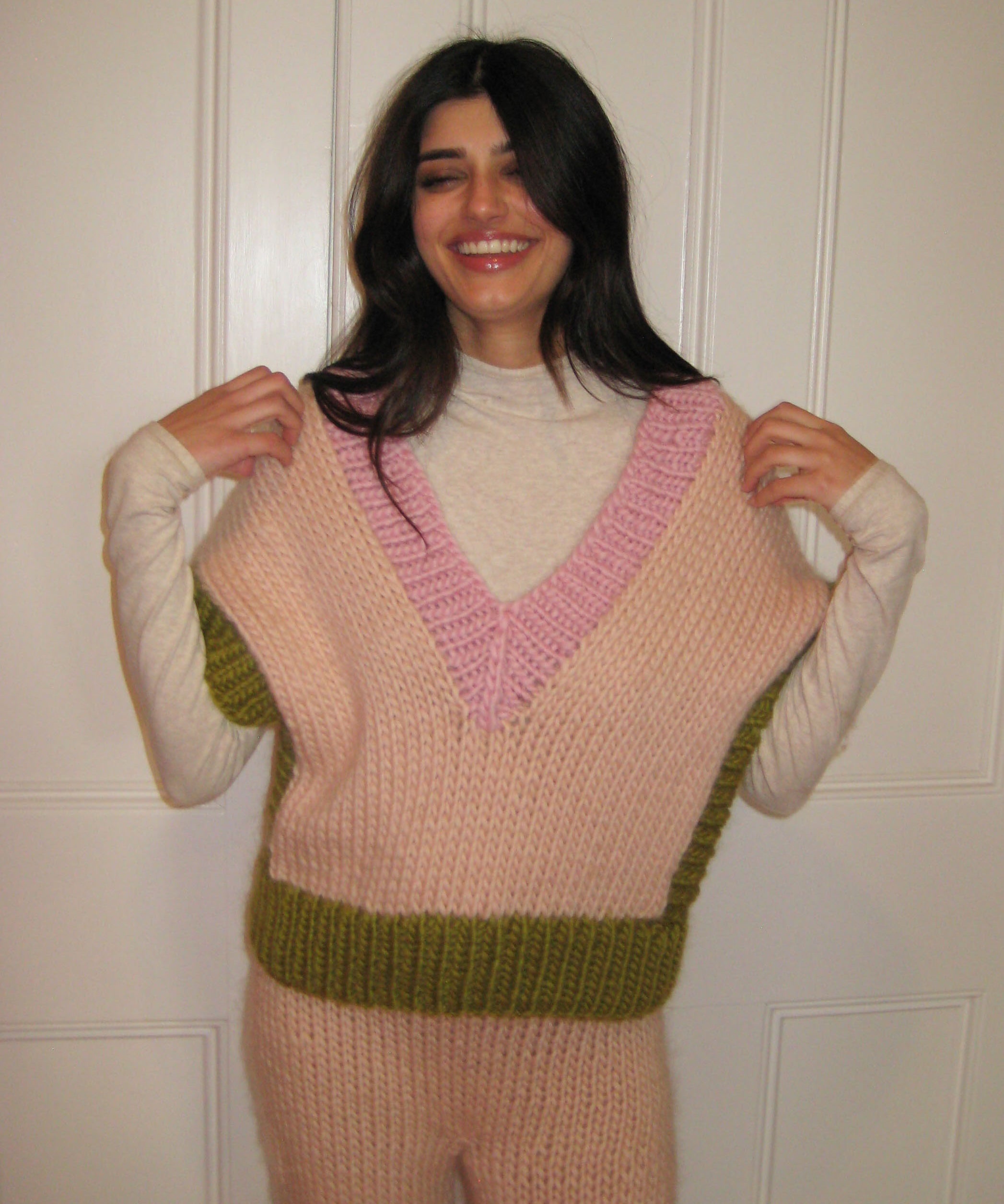 A woman wearing a colourful green, pink and cream vest