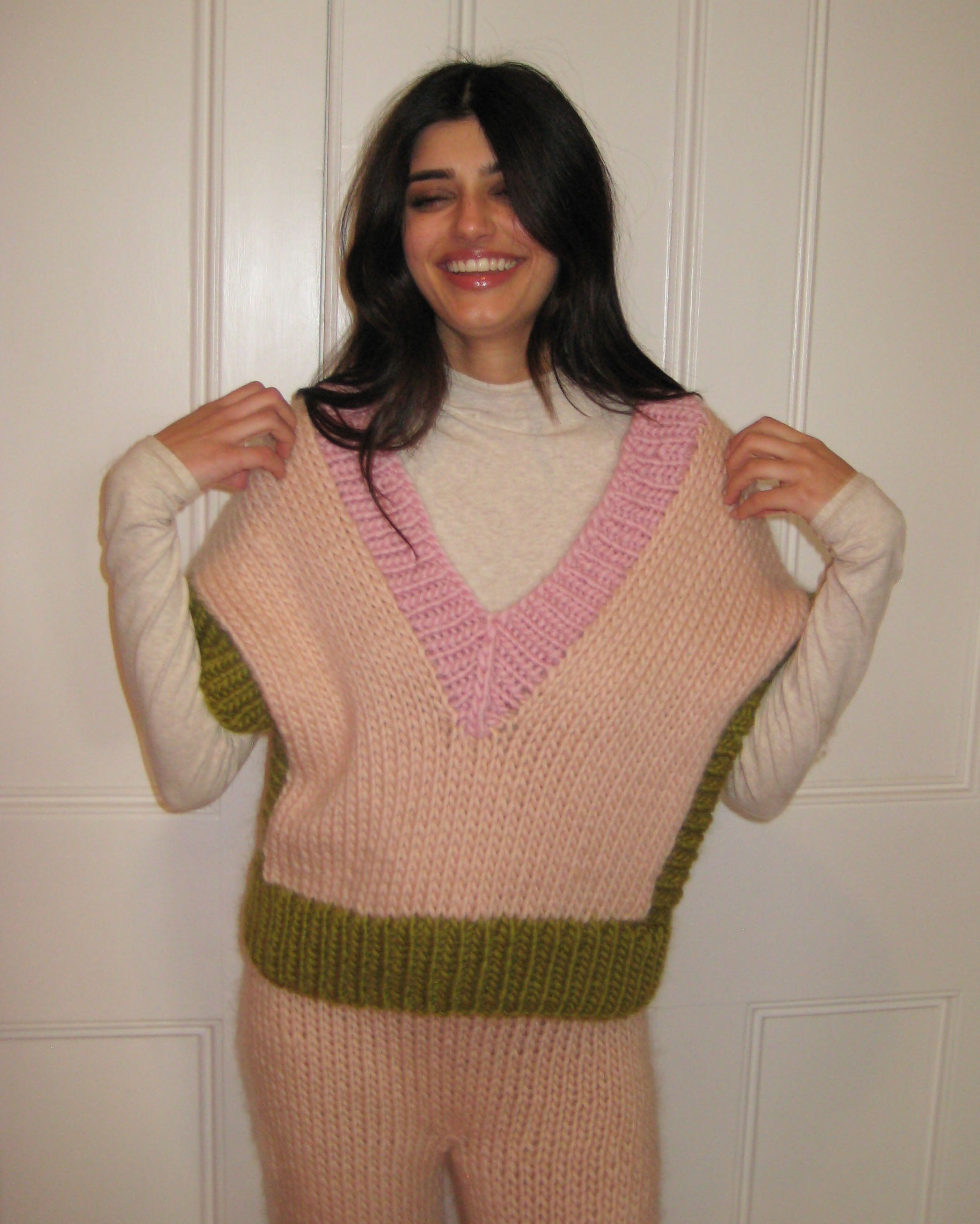 A woman wearing a colourful green, pink and cream vest