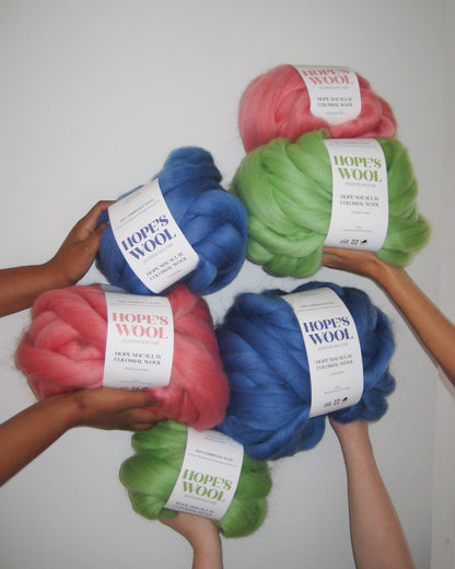 Hands holding up Balls of Corriedale wool in Pink, Blue and Green