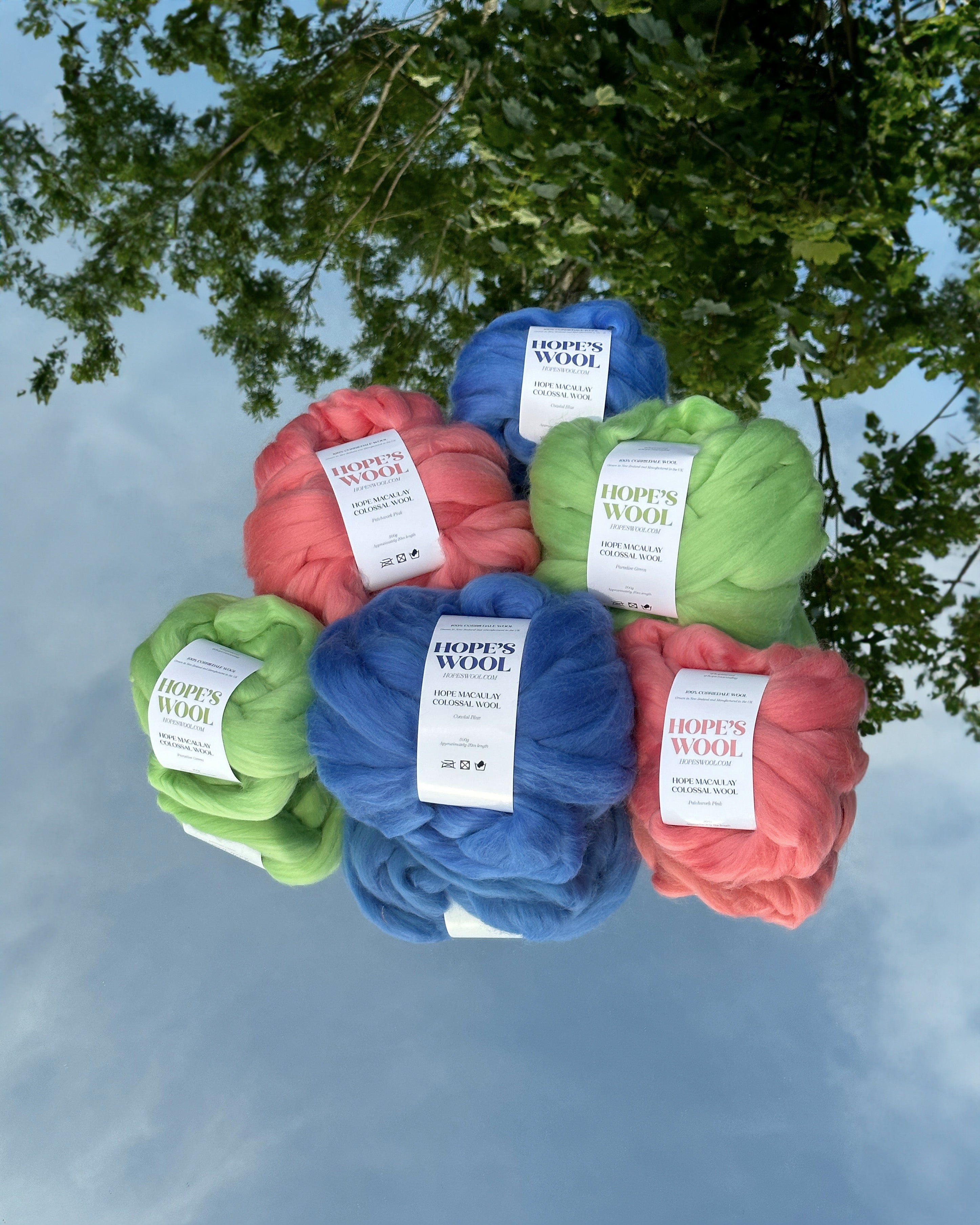 Balls of Corriedale wool in Pink, Blue and Green sitting on a mirror